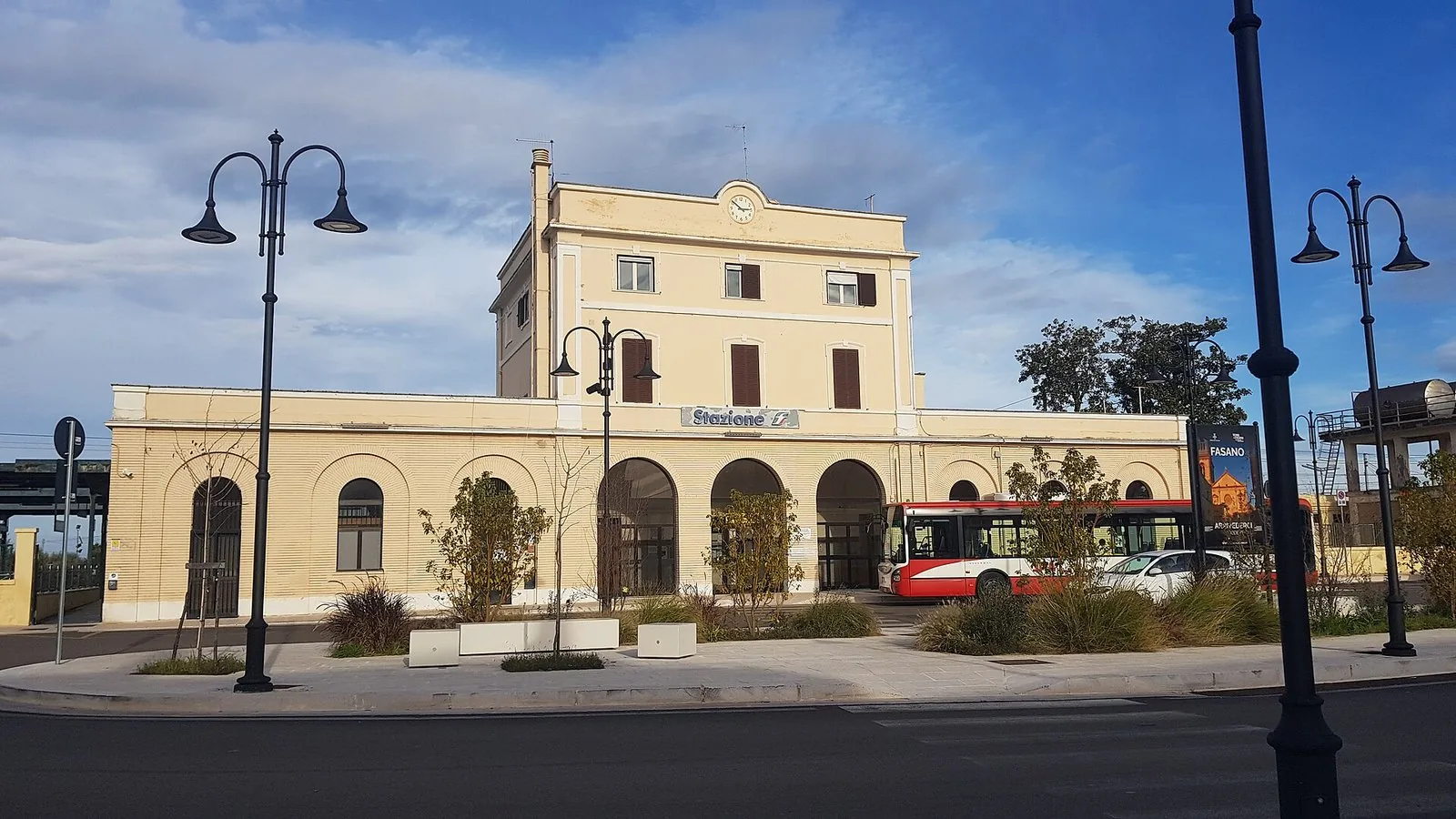 Facciata della stazione ferroviaria di Fasano con il piazzale e l'autobus di collegamento