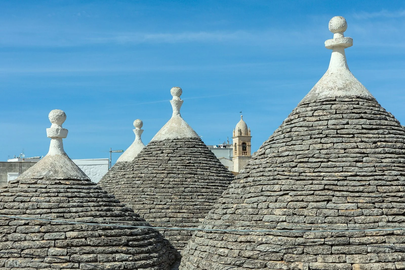 Dettaglio delle cuspidi dei trulli con il tetto in chiancarelle di pietra a secco e il pinnacolo bianco